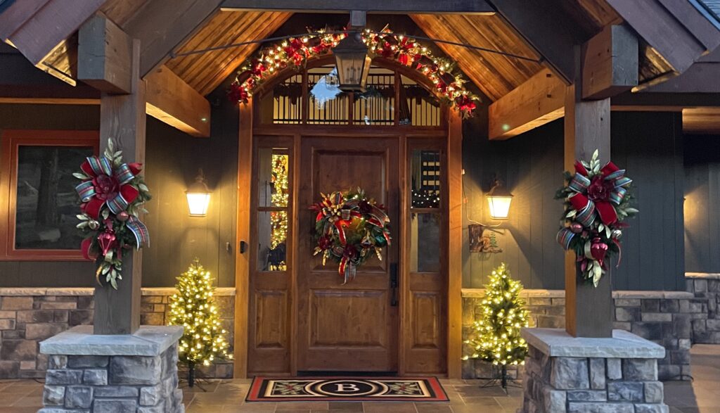 Beautifully decorated mountain home aglow with wreaths, garland and swags - with inside tree glowing in the background