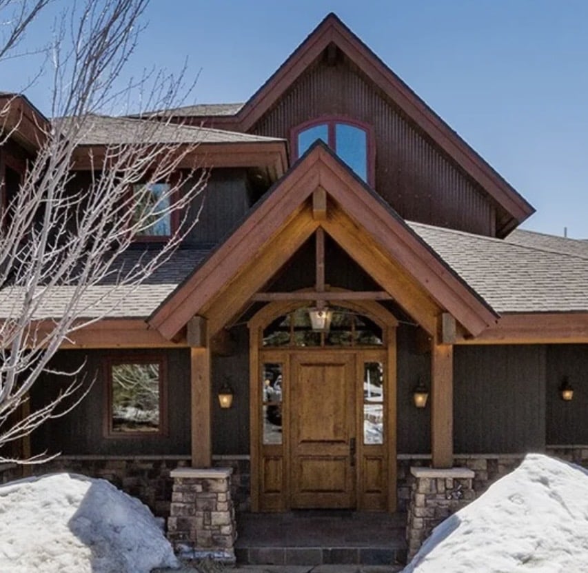 Mountain home in winter with snow covering most of the landscaping that makes it feel more inviting.