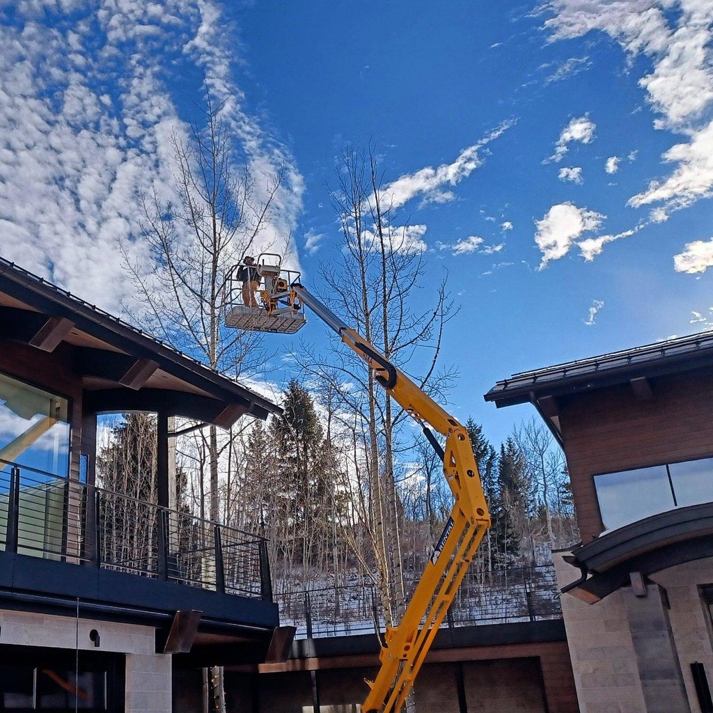 Outside lights being installed to the roof of a mountain house using a cherry picker machine